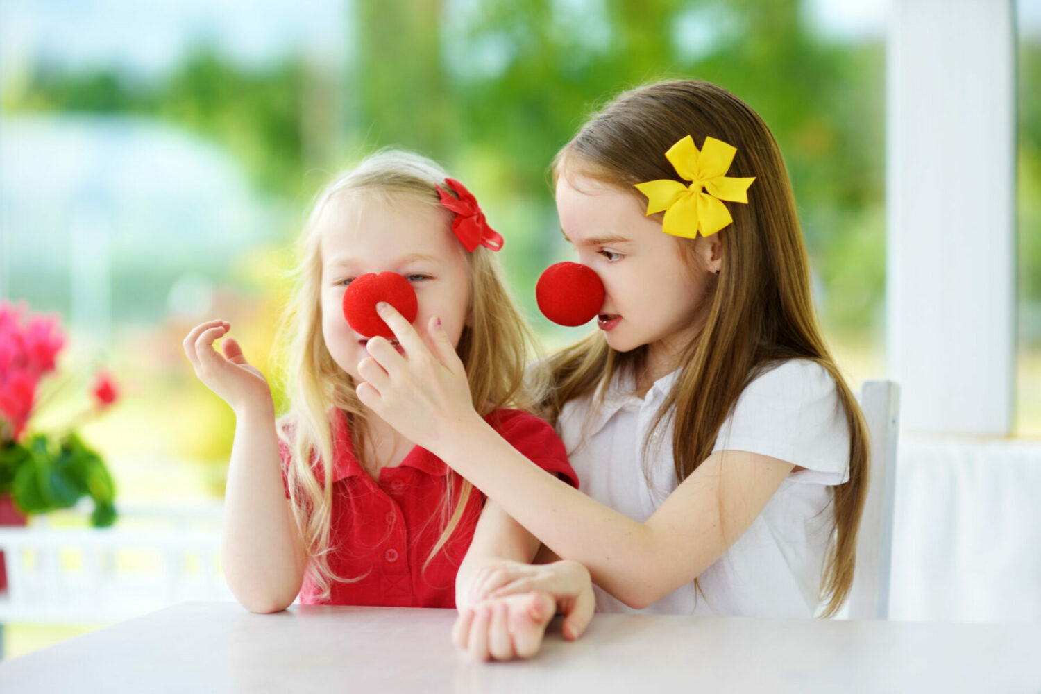 two young girls wearing red clown noses