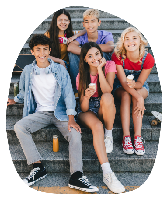 group of teens sitting on the steps of a building, smiling