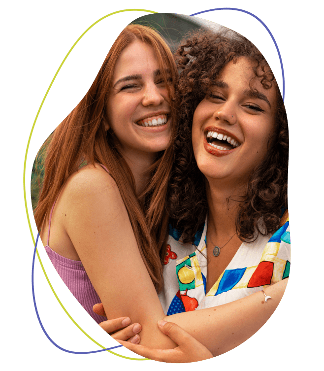 Two young woman smiling and hugging each other
